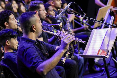 Músicos da orquestra se apresentando no palco do Evento GPA no Espaço Unimed em São Paulo, com destaque para um flautista tocando melodias durante a cerimônia.'