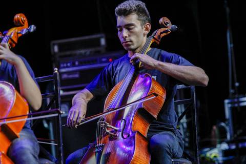 Violoncelista concentrado tocando seu instrumento no palco do Evento GPA no Espaço Unimed em São Paulo, contribuindo para a atmosfera orquestral da celebração.'