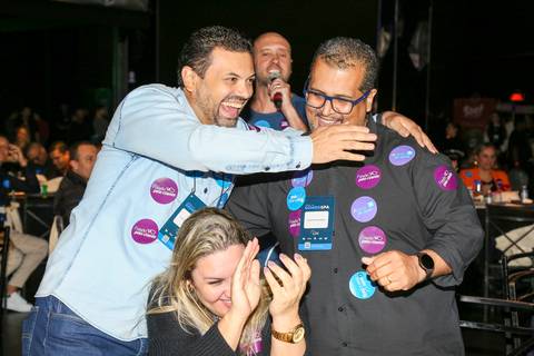 Convidados do Evento GPA interagindo e se cumprimentando no Espaço Unimed em São Paulo, após trocarem adesivos de engajamento, em um momento de networking e conexão.'