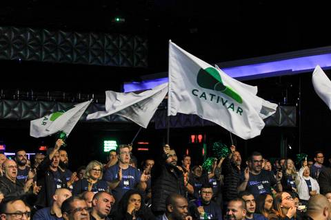Close-up de um grupo de convidados do Evento GPA balançando bandeiras, demonstrando entusiasmo e participação ativa no Espaço Unimed em São Paulo.'