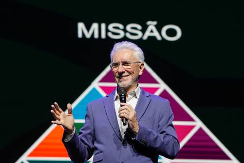 Eugenio Mussak no palco do Espaço Unimed em São Paulo, posicionado dentro de um gráfico em forma de triângulo no telão, com a palavra 'MISSÃO' no topo, ilustrando conceitos estratégicos para o Evento GPA'