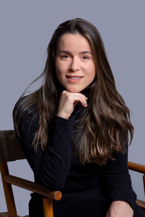 Jovem mulher em pose reflexiva, sentada e vestida de preto, apoiando o queixo na mão, em seu ensaio corporativo em São Paulo, destacando sua seriedade e foco.'