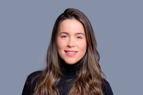 Close-up do rosto de uma jovem mulher, sentada e vestida de preto, com as mãos cruzadas no colo, destacando sua expressão séria e concentrada em ensaio corporativo em São Paulo.'