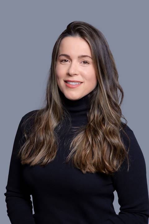 Retrato de uma jovem mulher em pé, olhando diretamente para a câmera com um sorriso sutil, em seu ensaio corporativo em São Paulo/SP.'