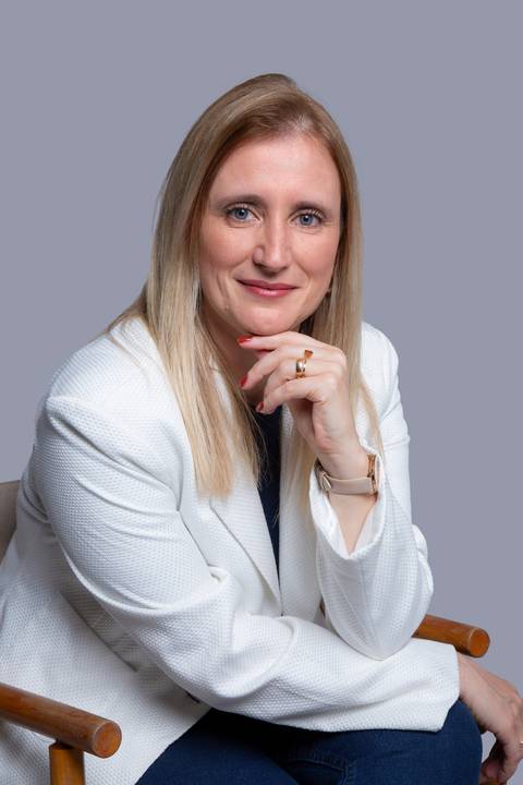 Mulher loira em pose pensativa, sentada em ensaio corporativo em São Paulo, apoiando o queixo nas mãos, transmitindo seriedade e profissionalismo.'