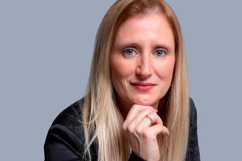 Close-up do rosto de mulher loira, com foco em sua expressão séria e concentrada, apoiando o queixo com os dedos, destacando detalhes de sua vestimenta corporativa preta e branca em São Paulo.'