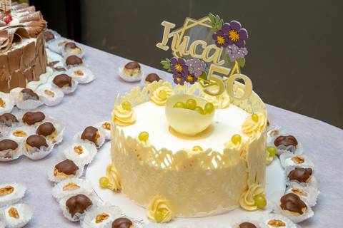 Bolo de aniversário da aniversariante de 50 anos, com design elegante e detalhes decorativos, posicionado na mesa principal do Restaurante Nanako em São Paulo.'