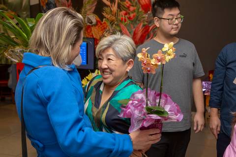 A aniversariante de 50 anos em uma conversa animada e sorridente com uma convidada, desfrutando da interação social no Restaurante Nanako em São Paulo.'