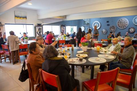 Convidados reunidos e interagindo nas mesas do Restaurante Nanako em São Paulo, celebrando o aniversário em um ambiente descontraído e alegre.'