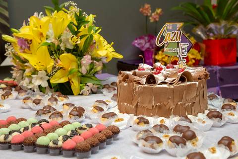 Bolo de aniversário do aniversariante de 41 anos, cercado por doces e delicadas flores, em destaque na mesa de celebração no Restaurante Nanako, São Paulo.'