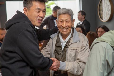 O aniversariante de 41 anos cumprimentando calorosamente um convidado no Restaurante Nanako em São Paulo, demonstrando a alegria e a hospitalidade da celebração.'