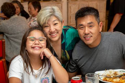 Os dois aniversariantes, a mulher de 50 e o homem de 41 anos, posando juntos com a filha do aniversariante, em um registro familiar especial no Restaurante Nanako em São Paulo.'