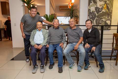 O aniversariante de 41 anos posando para uma foto em grupo com convidados, celebrando juntos no ambiente festivo do Restaurante Nanako em São Paulo.'