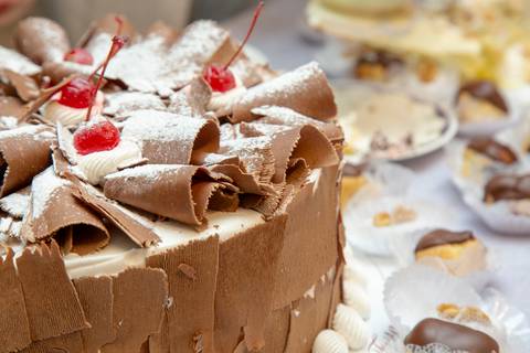 Plano fechado de um dos bolos de aniversário, revelando detalhes da cobertura e da decoração artística, parte da celebração no Restaurante Nanako em São Paulo.'