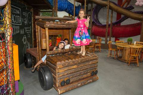 Crianças brincando sobre um caminhão de madeira no Buffet Vila Terracota durante a festa infantil com tema Lilo & Stitch. A imagem retrata diversão, aventura e interação lúdica no espaço externo.'