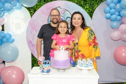 Pai, mãe e filha reunidos em frente à mesa do bolo na festa infantil com tema Lilo & Stitch no Buffet Vila Terracota, em São Paulo. A imagem retrata união familiar e um momento especial de celebração.'