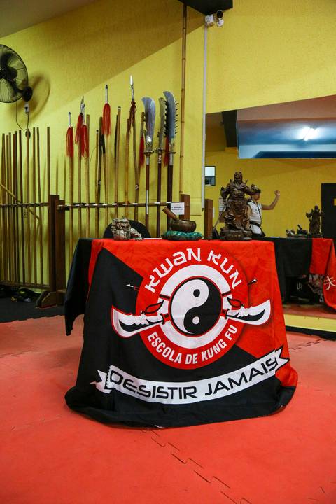 Mesa com a toalha oficial da Academia Kwan Kun preparada para o Exame de Faixa Preta em São Paulo. A imagem destaca a identidade visual da instituição, com composição simbólica que representa tradição, organização e respeito às artes marciais.'