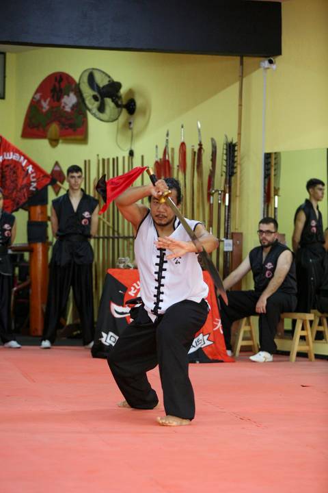 Participante do Exame de Faixa Preta na Academia Kwan Kun, em São Paulo, utilizando a espada em demonstração técnica. A imagem transmite precisão, disciplina e o legado das artes marciais, com destaque para a fluidez dos movimentos e o respeito à tradição'