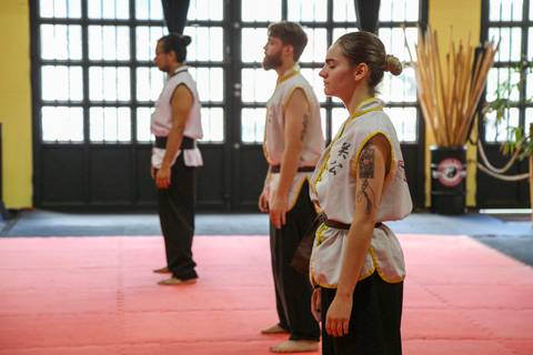 Três participantes em perfil, concentrados antes da execução técnica durante o Exame de Faixa Preta na Academia Kwan Kun, em São Paulo. A imagem destaca postura, foco e sincronia, refletindo a disciplina e a preparação mental exigidas pelas artes marciais'