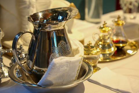 Detalhe da jarra litúrgica e dos elementos sagrados dispostos sobre o altar da Paróquia Universitária Beato Carlo Acutis, em São Paulo, durante a Celebração Catequética. A imagem revela a delicadeza da preparação ritual, com texturas, reflexos e significa'
