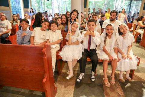 Grupo de crianças catequizandas, vestidas com suas vestes brancas, posando alegremente para uma foto no ambiente da Paróquia Universitária Beato Carlo Acutis em São Paulo, celebrando o momento da Celebração Catequética.'