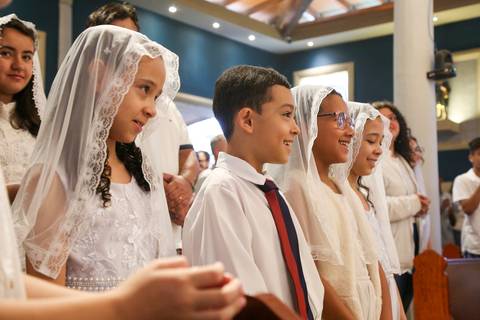 Expressão de alegria das crianças durante a Celebração Catequética na Paróquia Universitária Beato Carlo Acutis em São Paulo, com foco nos rostos iluminados pela emoção do momento, transmitindo fé, inocência e espiritualidade juvenil.'