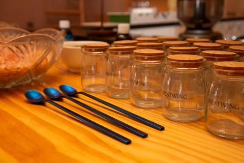 Itens e ingredientes organizados para o workshop de sais de banho no evento Westwing com influenciadores digitais no Clandestina Restaurante em São Paulo, incluindo potes com sais coloridos, ervas secas e essências aromáticas, prontos para a criação.'