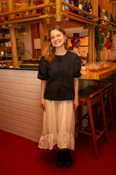 Participante do evento Westwing no Clandestina Restaurante em São Paulo, sorrindo e interagindo no ambiente sofisticado, refletindo o engajamento e a experiência exclusiva para influenciadores digitais.'