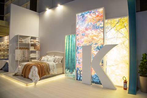 Letra K decorativa da Karsten em destaque no estande da ABUP Show 2025 no Distrito Anhembi, com um painel iluminado ao fundo exibindo uma elegante decoração de cama, realçando o design de interiores'