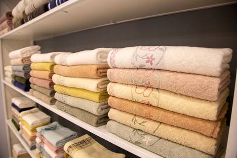 Exposição organizada de toalhas da Karsten no estande da ABUP Show 2025 no Distrito Anhembi, apresentando variedade de cores, texturas e tamanhos em linhas para banho e lavabo, destacando a qualidade e design da marca.'