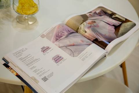 Catálogo da Karsten aberto sobre uma mesa no estande da ABUP Show 2025 no Distrito Anhembi, São Paulo, exibindo as novas coleções de produtos para casa e decoração, convidando à exploração do design.'