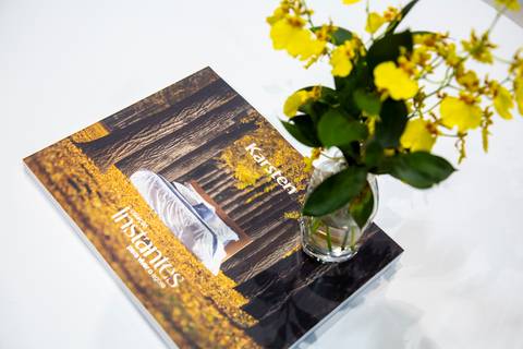 Catálogo fechado da Karsten em exposição no estande da ABUP Show 2025 no Distrito Anhembi, com um elegante vaso de flor decorando-o, exibindo o estilo da marca'