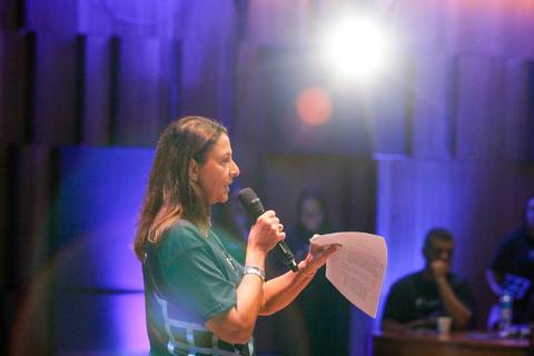 Visão do palco do Teatro B32 em São Paulo: diretora da Plurix discursando para a plateia durante o evento corporativo, com foco na apresentação e no público'