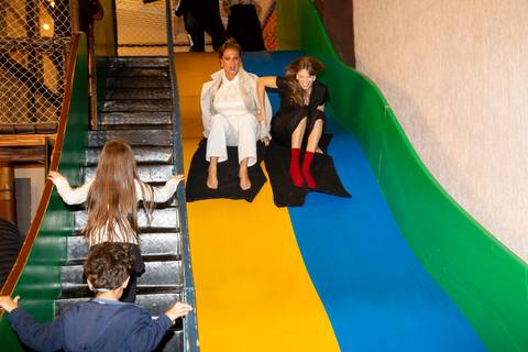 Mãe e filha descendo juntas em um escorregador grande e colorido no Kid Recanto Buffet em São Paulo, ambas com expressões divertidas e sorrindo, aproveitando a festa de aniversário infantil'