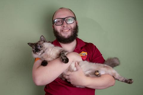 Filho segurando sua gatinha de pelo claro e rosto malhado, em um momento de carinho e conexão com o animal de estimação em ensaio de família em Mauá'