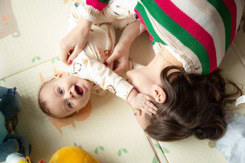 Mãe e bebê interagindo e brincando no tapetinho de atividades em ensaio de família em SP'