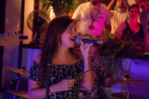 Vocalista da banda Madressilva em destaque no palco, cantando com um sorriso e transmitindo a energia da performance. (reFestança, São Paulo) fotografia Bruno Arita'