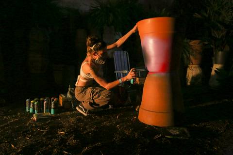 Artista engajada em living painting, pintando um vaso grande de barro em uma área externa do evento. (reFestança, São Paulo) fotografia Bruno Arita'