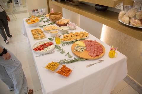 Mesa farta de comidas diversas, disposta para os convidados se servirem durante a festa de aniversário em São Paulo.'
