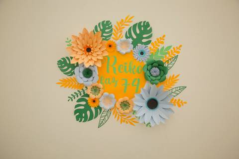 Painel decorativo com uma bela arte floral e a inscrição 'Reiko faz 74', em destaque no salão de festas de aniversário em São Paulo.'