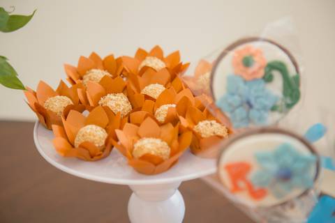 Close-up de docinhos variados e coloridos, arranjados elegantemente na mesa de aniversário, convidando os convidados a se servirem.'