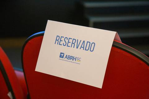 Placa 'RESERVADO' com o logo da ABRH SC em um banco, indicando a organização do evento. Fotografia Bruno Arita'