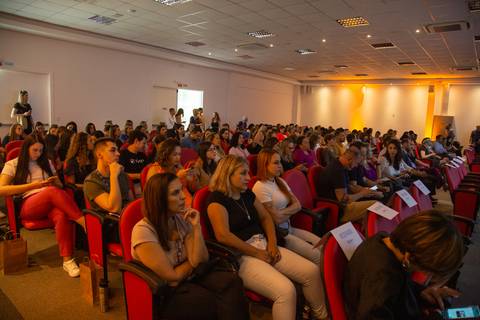 Público do Fórum Equilíbrio da ABRH SC sentado nas cadeiras, com foco nas pessoas atentas à apresentação no palco. Fotografia Bruno Arita'