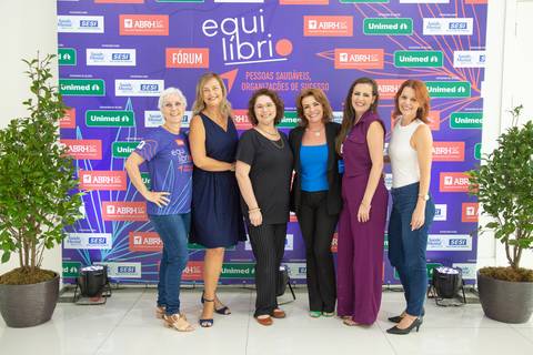 Participantes do Fórum Equilíbrio da ABRH SC posando para uma foto em grupo no painel backdrop do evento. Fotografia Bruno Arita'
