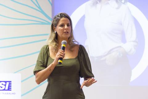 Palestrante mulher falando no palco do Fórum Equilíbrio da ABRH SC, transmitindo sua mensagem com clareza e presença. Fotografia Bruno Arita'