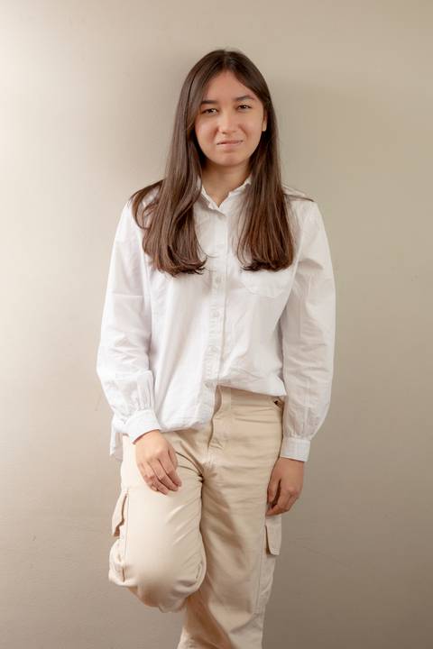 Retrato da filha adolescente (camisa branca e calça creme) em pose natural e despojada, com um pé encostado na parede, transmitindo sua personalidade. (Ensaio de Família, São Paulo, Fotógrafo Bruno Arita)'