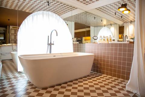 Banheiro com uma banheira branca elegantemente iluminada ao fundo, exibindo o design sofisticado do espaço Casa Riachuelo na CASACOR São Paulo 2025. (Evento Casa Riachuelo CASACOR 2025, São Paulo, Fotos Bruno Arita)'