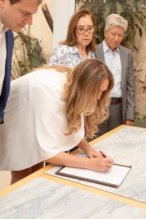 Plano fechado da noiva assinando os documentos, com uma expressão concentrada. (Casamento Civil, São Paulo, Fotógrafo Bruno Arita)'