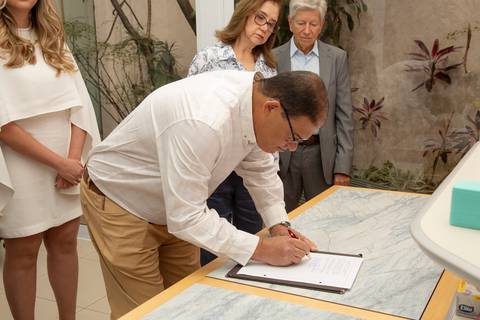Padrinho assinando os documentos, sob o olhar dos outros padrinhos presentes na cerimônia. (Casamento Civil, São Paulo, Fotógrafo Bruno Arita)'