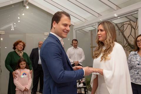 Noivo, sorrindo e olhando para a juíza, repetindo as palavras enquanto coloca a aliança na mão da noiva. (Casamento Civil, São Paulo, Fotógrafo Bruno Arita)'